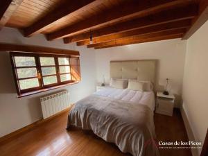 RuenesVivienda vacacional El Cau - Casas de Los Picos的一间带一张大床的卧室,位于一个拥有木制天花板的房间