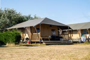 比伦Glamping Ameland的田野上带门廊的大型帐篷