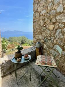 卡尔热斯charmante bergerie à Cargese tres belle vue mer avec jardin的一张桌子和一把椅子,坐在石墙旁