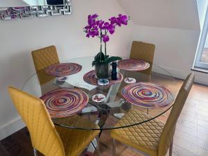 普里茅斯Seascape Penthouse with Free Parking的玻璃桌,椅子和花瓶,紫色花朵