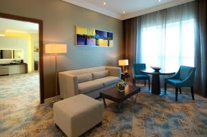 迪拜Elite Byblos Hotel的客厅配有沙发、椅子和桌子