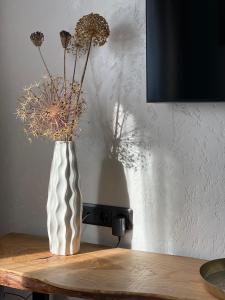 阿卢克斯内Apartamenti Ezera Pērle的白色花瓶,桌子上放着干花