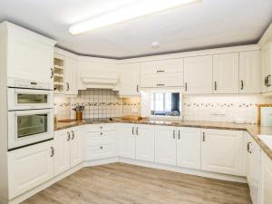 曼海德Oxford House的白色的厨房配有白色的橱柜和木地板。