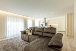埃斯波森迪Apartamento Bela Vista - Minho's Guest的一间带棕色沙发的客厅和一间厨房