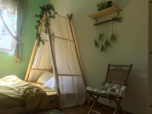 大叻Whispering Pines Dalat (Thông Thì Thầm ĐL)的一间卧室配有一张天蓬床和一把椅子
