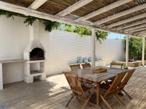 托雷拉皮罗Villa Teresa - giardino privato的天井配有木桌和户外烤箱。