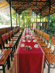 Kon TumHomestay Nang Nghieng的一张长桌子,上面有红色的桌布和椅子