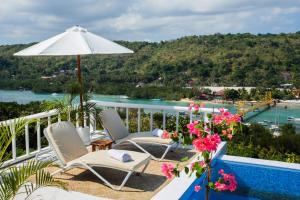 蓝梦岛Stardust Villas的一个带椅子和遮阳伞的阳台以及一个游泳池。