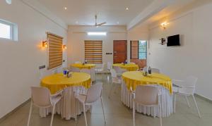 科钦Treebo Trend Amigos Residency的用餐室配有黄色桌子和白色椅子
