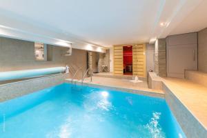 鸽林Magnifique Villa - Piscine-Sauna- Grand Jardin -15 personnes -Entièrement Climatisée - Cadre Exceptionnel的浴室设有大型蓝色游泳池,配有浴缸