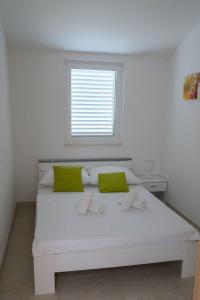 特罗吉尔Villa Vinko的一张带绿色枕头的白色床和窗户