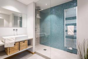 卢森堡Renovated 2 Bedroom Apartment with Parking & AC的一间带水槽和玻璃淋浴的浴室