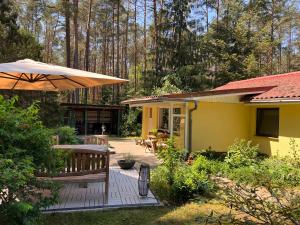 BorkwaldeFerienhaus im Wald的黄色的房子,配有长凳和雨伞