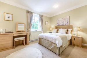 拜伯里Cotteswold House的一间卧室配有一张床、一张书桌和一面镜子