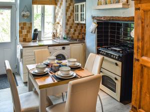 多尔顿因弗内斯Beeswax Cottage的厨房配有桌椅和炉灶。