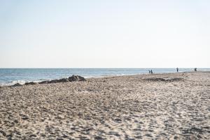 比伦Glamping Ameland的沙滩上的人在沙滩上和大海上散步
