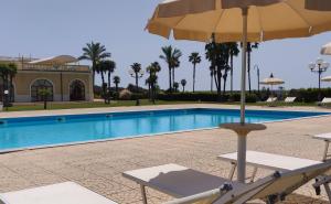 罗切拉伊奥尼卡帕可德普林西皮酒店的游泳池旁带遮阳伞的椅子