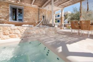 VathíTERRA E SOLE spa suite Aegina的庭院设有游泳池、桌子和椅子。