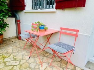 图卢兹Sweet Home - 55m2 appt, garden, swimming pool, parking的两张红色椅子和一张粉红色的桌子及椅子