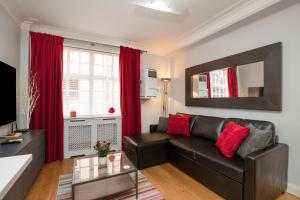 伦敦Modern Quiet 1 bed Flat -Mayfair的客厅配有真皮沙发和红色窗帘
