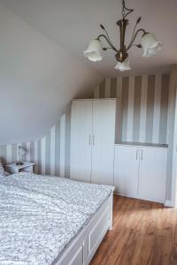 文戈热沃Ostoja Zielonki的一间卧室配有一张床、白色橱柜和吊灯。