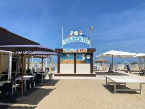 里米尼chiAma Hotel的海滩上的一个标志,上面有桌子和遮阳伞
