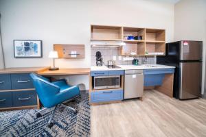 查尔斯顿Candlewood Suites Charleston – Mt. Pleasant, an IHG Hotel的厨房配有蓝色椅子和冰箱