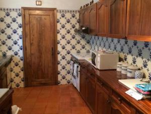 巴塞卢什Casa Mata da Ribeira的厨房配有蓝色和白色的壁纸和微波炉