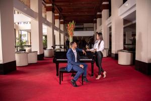 圣何塞圣何塞巴塞罗酒店的坐在钢琴上的男人和女人