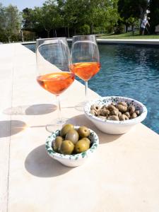 奥特朗托Podere 43 Charme B&B的两杯酒,紧挨着一碗橄榄和一碗坚果
