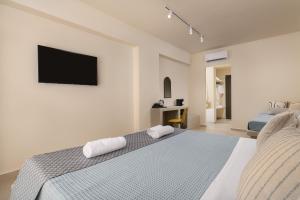 拉多斯橄榄园酒店的卧室配有一张床铺,墙上配有电视