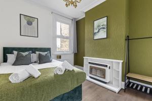 伦敦Parea Living - Hackney, 4-Bedroom Victorian House w Big Garden的绿色卧室设有1张床和1个壁炉