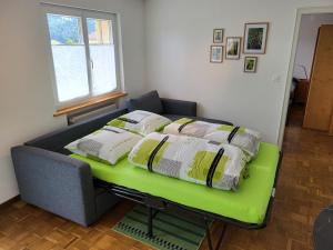 TramelanLes petits Rosiers的一张床上的床铺,床上的绿色长凳上配有枕头