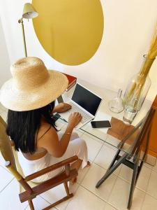 萨尔瓦多Casa de praia no Flamengo的坐在一张桌子上手提电脑的稻草帽上的女人