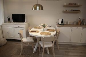 斯诺科Apartamenty nad Zalewem 213的厨房配有白色的桌椅和电视。