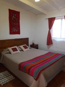 圣佩德罗·德·阿塔卡马Casa Sutar Los Pimientos的一间卧室配有一张带彩色毯子的床
