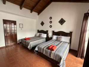 危地马拉安地瓜Casa Los Habitantes Antigua Guatemala的一间卧室配有两张带红色枕头的床