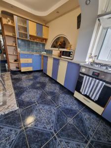阿尔杰什河畔库尔泰亚Emily Residence的厨房配有蓝色和黄色的橱柜,铺有瓷砖地板。