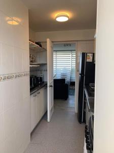 瓦尔帕莱索Hermoso departamento de 2 dormitorios con una vista maravillosa的厨房配有白色橱柜和黑色冰箱。