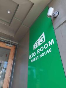 大阪BIG ROOM GUEST HOUSE的一间大房间旅馆墙上的绿色标志