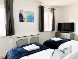 梅尔克舍姆Turners Court的一间卧室配有两张床和一台平面电视