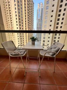 迪拜Robin Beach Hostel JBR的阳台配有桌椅,拥有高大的建筑