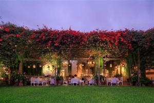 利马Hermoso departamento en pueblo libre cerca al aeropuerto的花园设有桌子和红色的鲜花及椅子