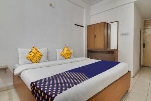 海得拉巴SPOT ON Apsara Hotel的一间卧室配有一张大床,提供黄色和蓝色的枕头