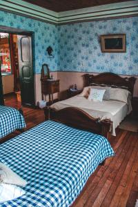 瓜斯卡Hotel Finca el Recreo的一间卧室配有两张床,铺有蓝色的壁纸。