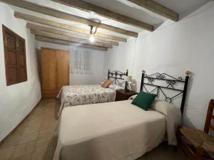 马拉加Casa rural Las Casillas的配有白色墙壁和木制天花板的客房内的两张床