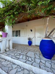 科孚镇Cozy Corfu Bungalow 5 minutes to Aqualand的石头庭院上两只蓝色花瓶的房子