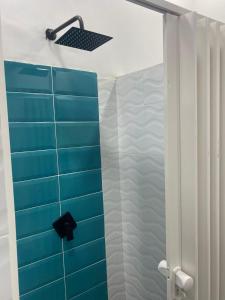 麦德林Hotel Hostal Caps San Diego的浴室铺有蓝色的墙壁瓷砖,配有淋浴。