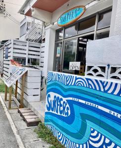 北谷町Surfer's Cafe& Hostel的冲浪店的一侧有标志