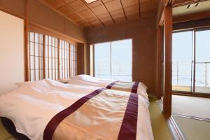 河津町Kaiyutei的配有2扇窗户的客房内的1张床